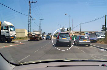 תמונה לשאלת תיאוריה: נתיב נסיעתך נחסם על ידי הרכב הכסוף החונה בחנייה כפולה (מסומן בעיגול). מה עליך לעשות?