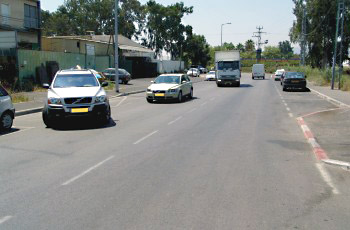 תמונה לשאלת תיאוריה: בתמונה שלפניך, תגובת הנוהגים בדרך לרכב היוצא מהחנייה אינה ברורה. כיצד צריך להגיב נהג המשאית במצב זה?